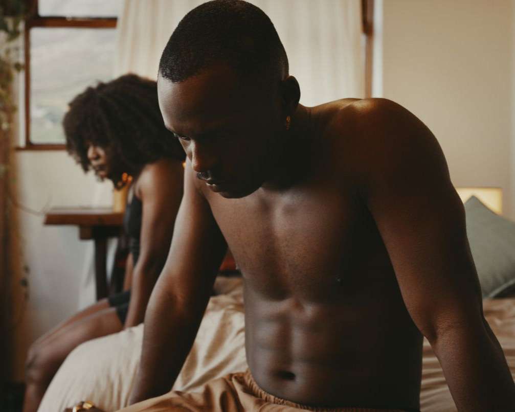 Man appearing upset in bedroom, illustrating the emotional impact of erectile dysfunction