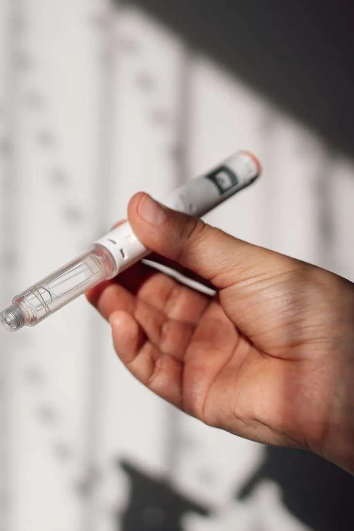 Patient holding a GLP-1 injection pen while exploring future retatrutide weight loss treatment options in San Diego.