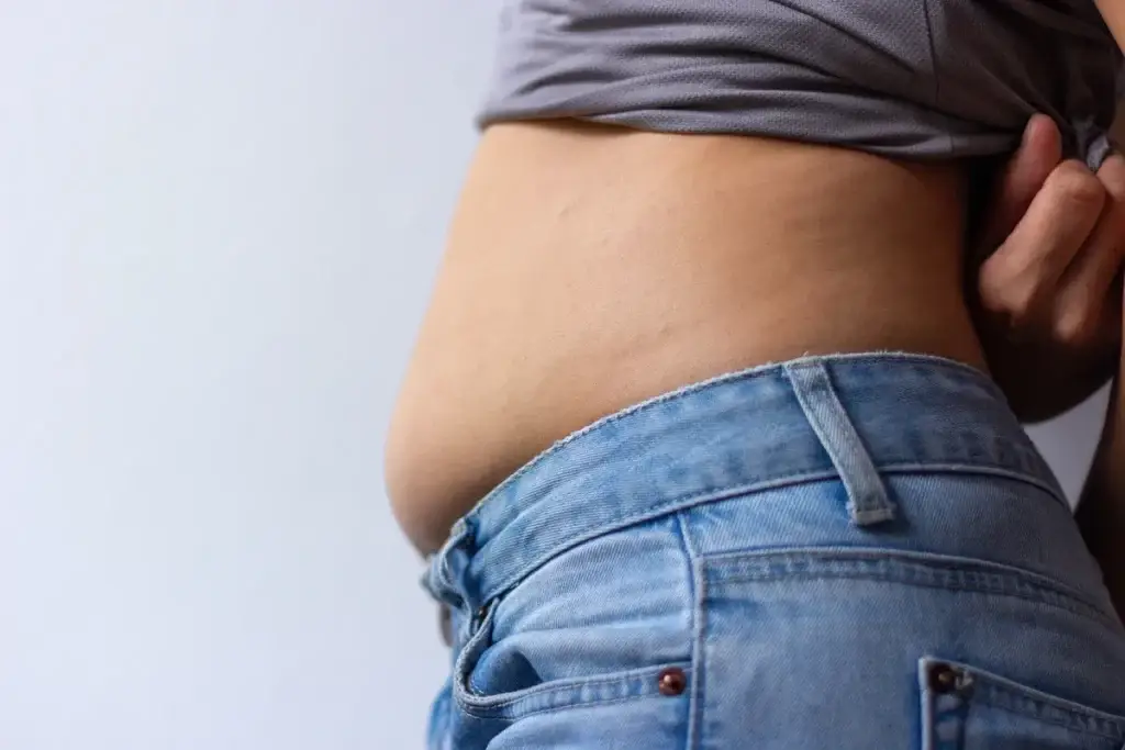 Woman protruding her stomach comparing bloating vs belly fat concerns
