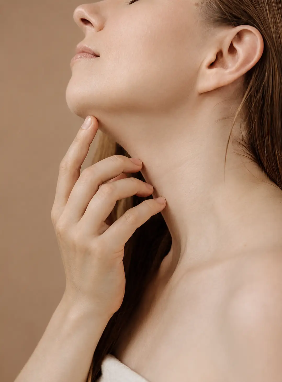 Woman touching her jawline showing firm facial contours before age related skin laxity and jowls develop